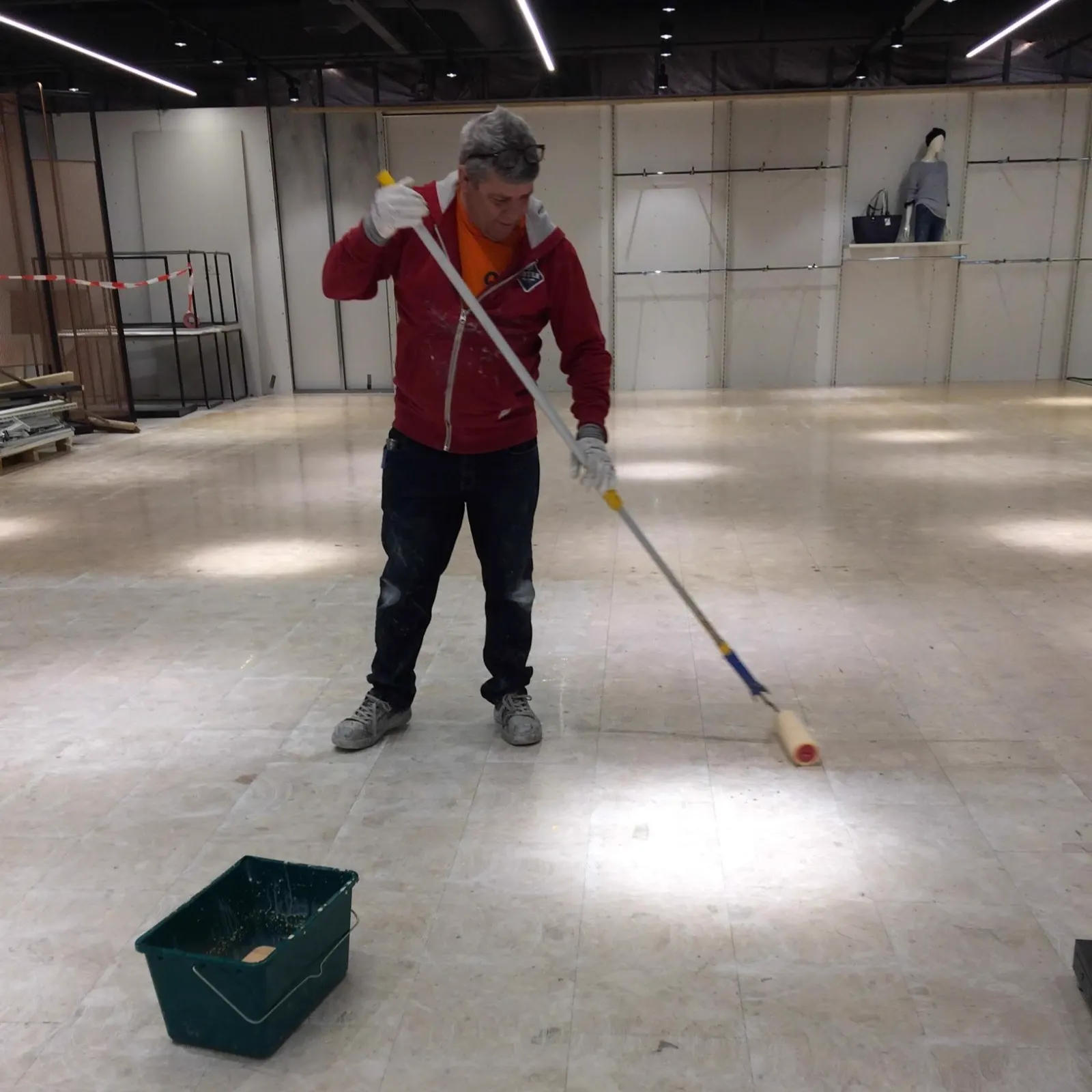 Leen Nugteren brengt met een roller voorstrijk aan op een winkelvloer